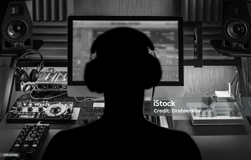 Man produce electronic music in project home studio. Black and white monochrome image