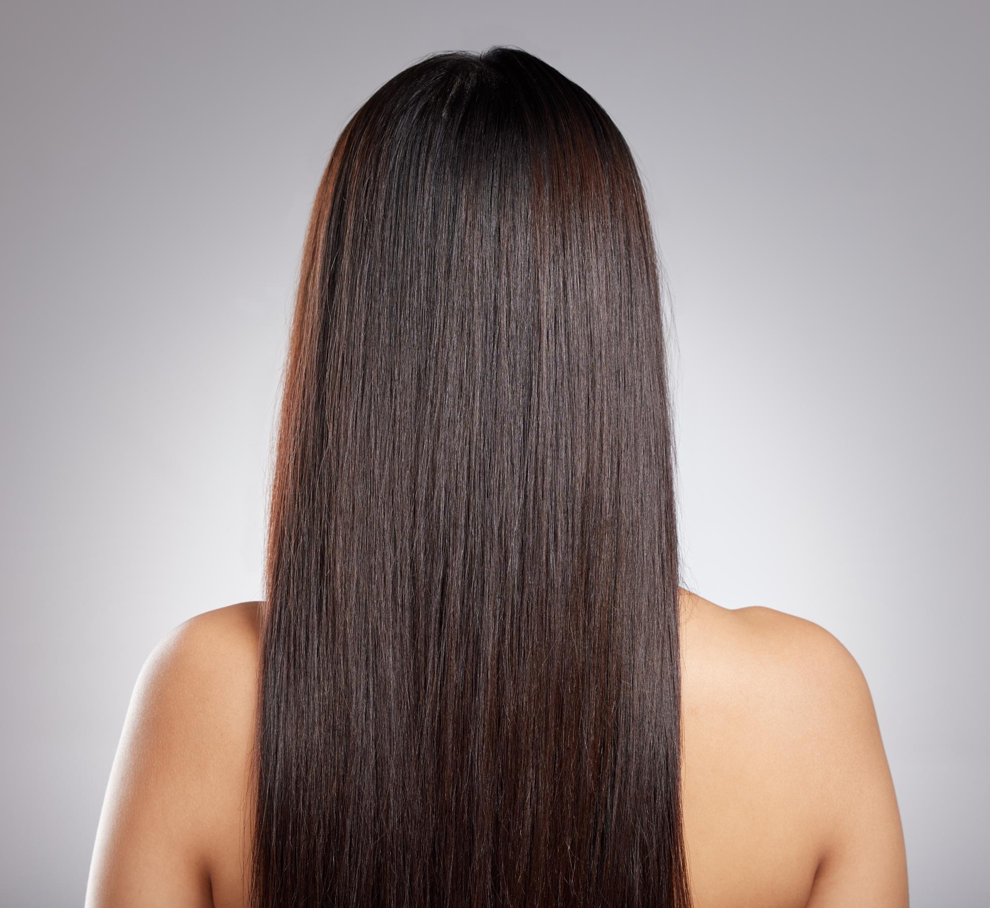 Simply sleek strands. Rearview shot of a young woman with long silky hair posing against a grey background. Adobe Stock Image available through Education License - Standard Image 
