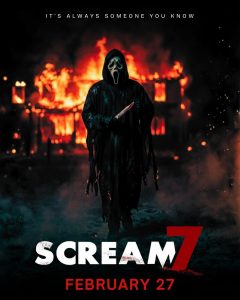 Hooded killer holding a knife walks towards viewer while a house burns down in the background.