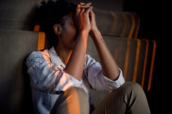 A woman seen in the photo crying, and holding her face, face is not visible.