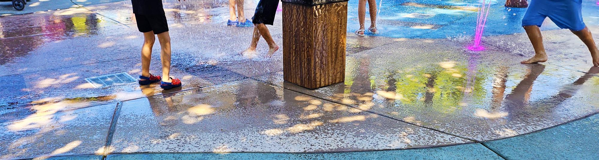 Children run and splash as waterworks begin flowing, filling the air with laughter and amusement.