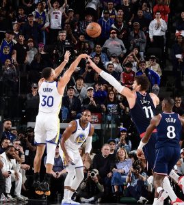 Professional basketball players (Golden State Warriors) playing, while being watched and photographed by a large cheering crowd. 