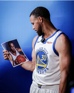 Curry looking at a photo of his younger self, with a blue background