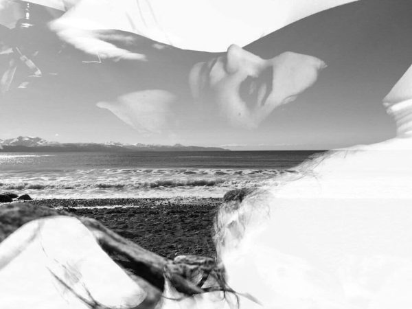 An artsy portrait. Black and white photograph. Girl seen, laying down, side profile, blended with a picture of a beach.